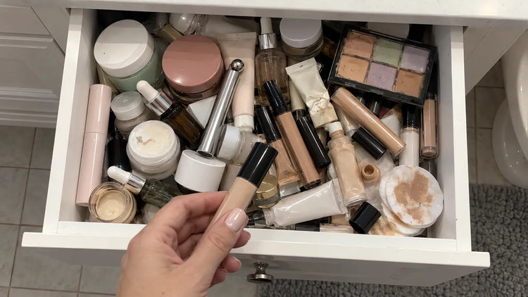 A woman in her 50s adds one more eye cream to a bathroom drawer full of eye creams, serums and concealers that did not fix her dark circles