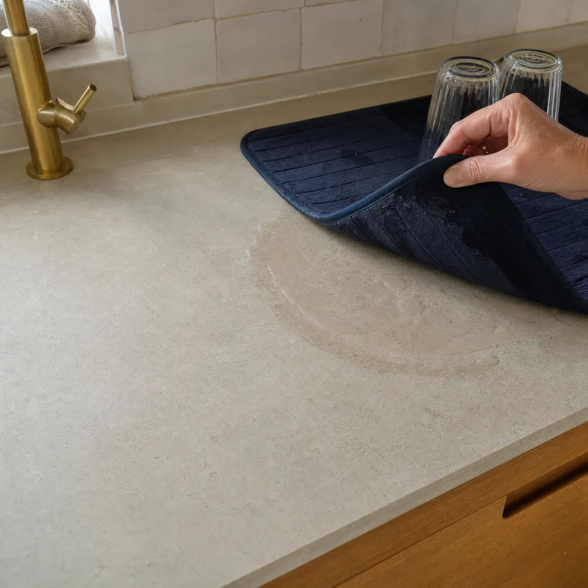 A cloth dish mat lifted off the counter, wet underneath