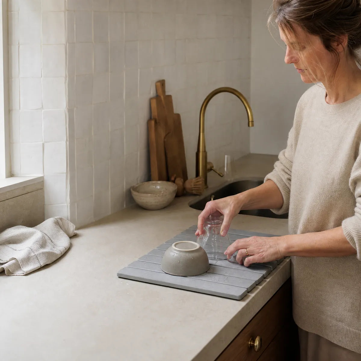 A woman setting a glass on the Sovara stone drying mat